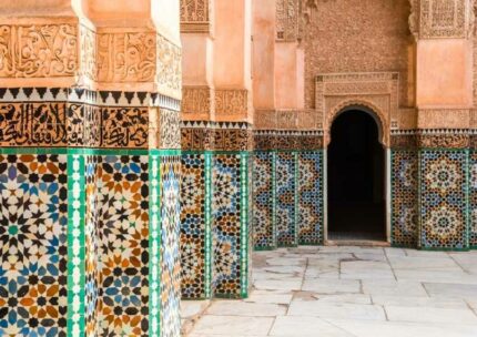 Zellige-tiled pillars and carved stucco around the courtyard of the Ben Youssef Madrasa in Marrakech