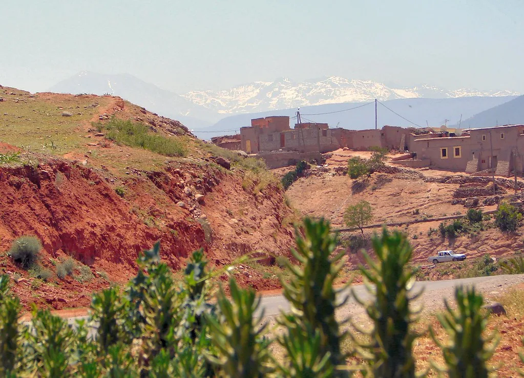 Ourika village on a red eroded hillside with snow-capped High Atlas peaks in the background Ourika village on a red eroded hillside with snow-capped High Atlas peaks in the background