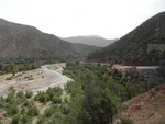 Hazy view over the Ourika riverbed, with a mountain road and grazing animals