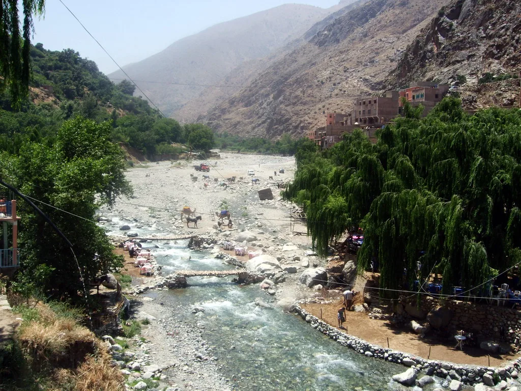 Berber village on the Ourika riverbed, with camels and donkeys crossing near riverside cafés Berber village on the Ourika riverbed, with camels and donkeys crossing near riverside cafés