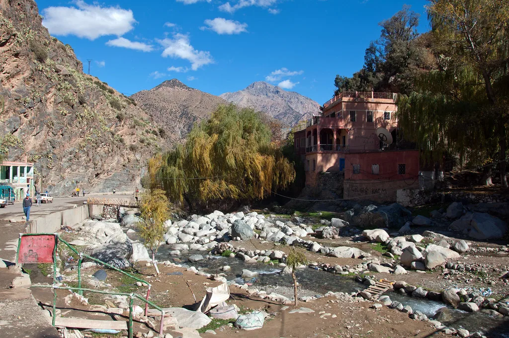 Pink guesthouse beside the Ourika riverbed with mountains rising behind Pink guesthouse beside the Ourika riverbed with mountains rising behind
