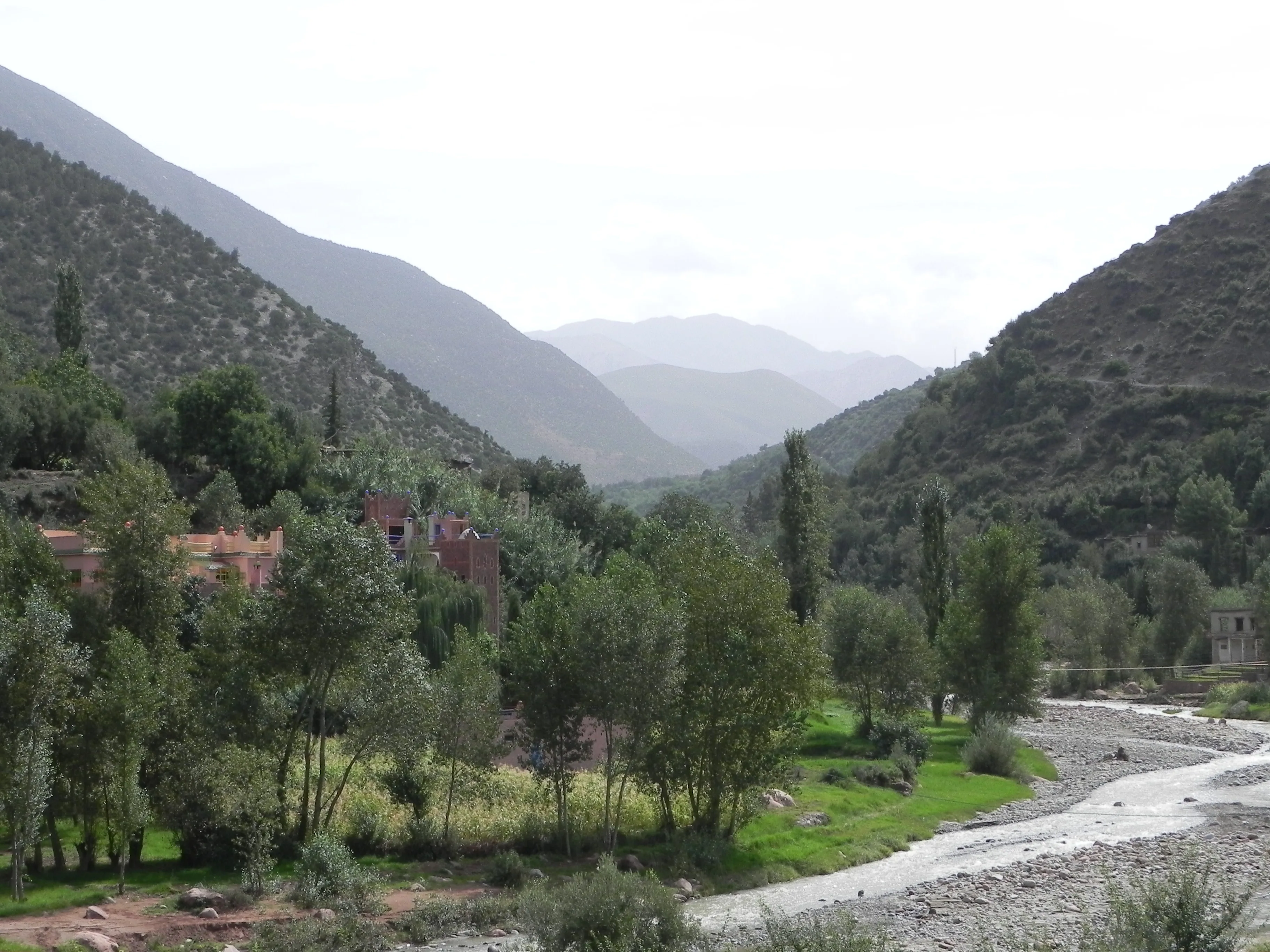 Ourika Valley village among poplar trees beside the riverbed, with hazy Atlas peaks in the distance Ourika Valley village among poplar trees beside the riverbed, with hazy Atlas peaks in the distance