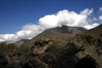Rocky outcrop in the foreground with clouds parting to reveal a High Atlas summit above