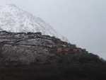 Berber village perched on a ridge near Imlil below a snow-dusted mountain under misty skies