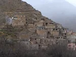 Closer view of a stacked stone and mudbrick Berber village on a mountainside near Imlil, with a hazy peak beyond
