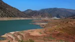 Ouirgane Lake with its dry-season red shoreline exposed beneath pine-covered mountains