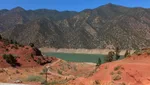 Red eroded hillside dropping to the turquoise waters of Ouirgane Lake