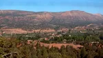 Panoramic view over the Ouirgane valley, with a village, orchards and layered red High Atlas ridges