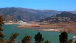 Ouirgane Lake with a rocky point projecting into the turquoise water and hazy High Atlas peaks beyond