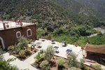 Guesthouse terrace with tables and chairs overlooking a green river valley in Ouirgane