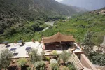 Guesthouse terrace with a traditional Berber tent canopy overlooking the green Ouirgane valley and river