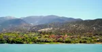 Village nestled among olive and poplar trees on the shore of Ouirgane Lake, with High Atlas peaks behind